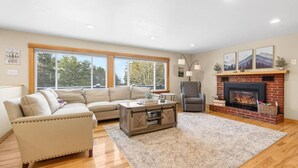 A living room with a sectional sofa, a fireplace, and a large window. - Updated 4BR, Game Room/Bar, Private, Near Gunstock (Gilford)