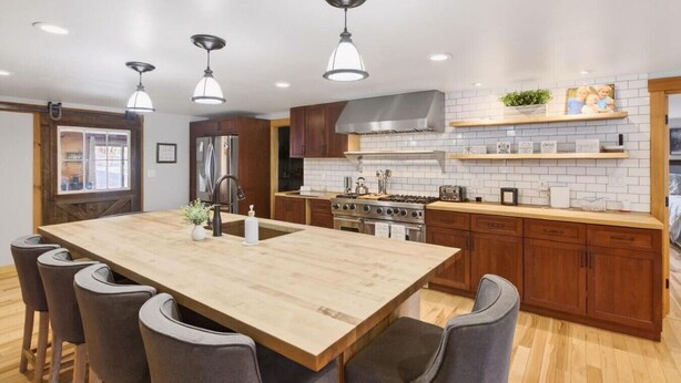 A modern kitchen with a large island, wooden cabinets, stainless steel appliances, and pendant lighting. - Updated 4BR, Game Room/Bar, Private, Near Gunstock (Gilford)