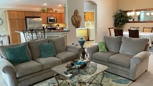 Ein Wohnzimmer mit zwei Sofas, einem Couchtisch und einer Küche im Hintergrund.