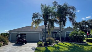 A residential house with a driveway, a golf cart, and a well-maintained lawn.