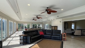 A spacious living room with a sectional sofa, a fireplace, and multiple ceiling fans.