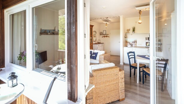 A cozy interior with wicker furniture, a dining area, and a kitchen. - Immenhagen (Malente)