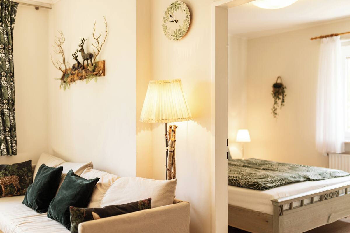 Una habitación acogedora con cama, una silla, una lámpara y un reloj de pared.