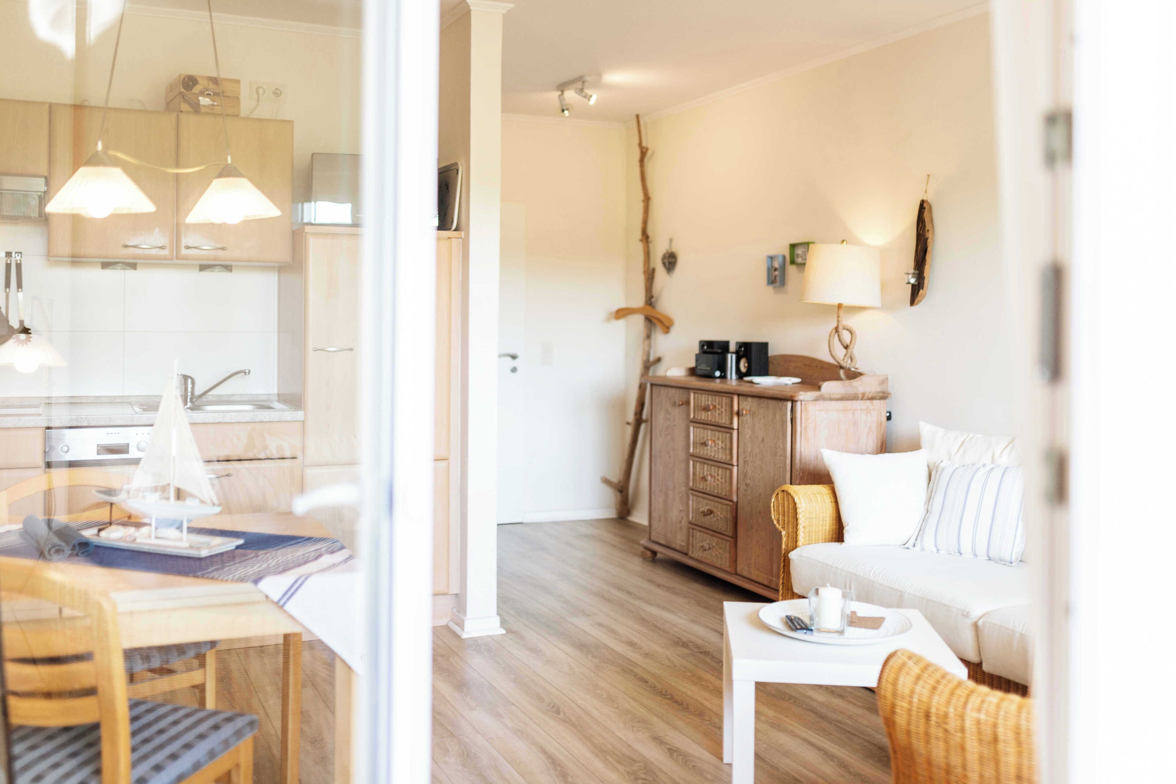 Une cuisine moderne avec des meubles blancs, une table à manger avec des chaises et un plancher en bois.