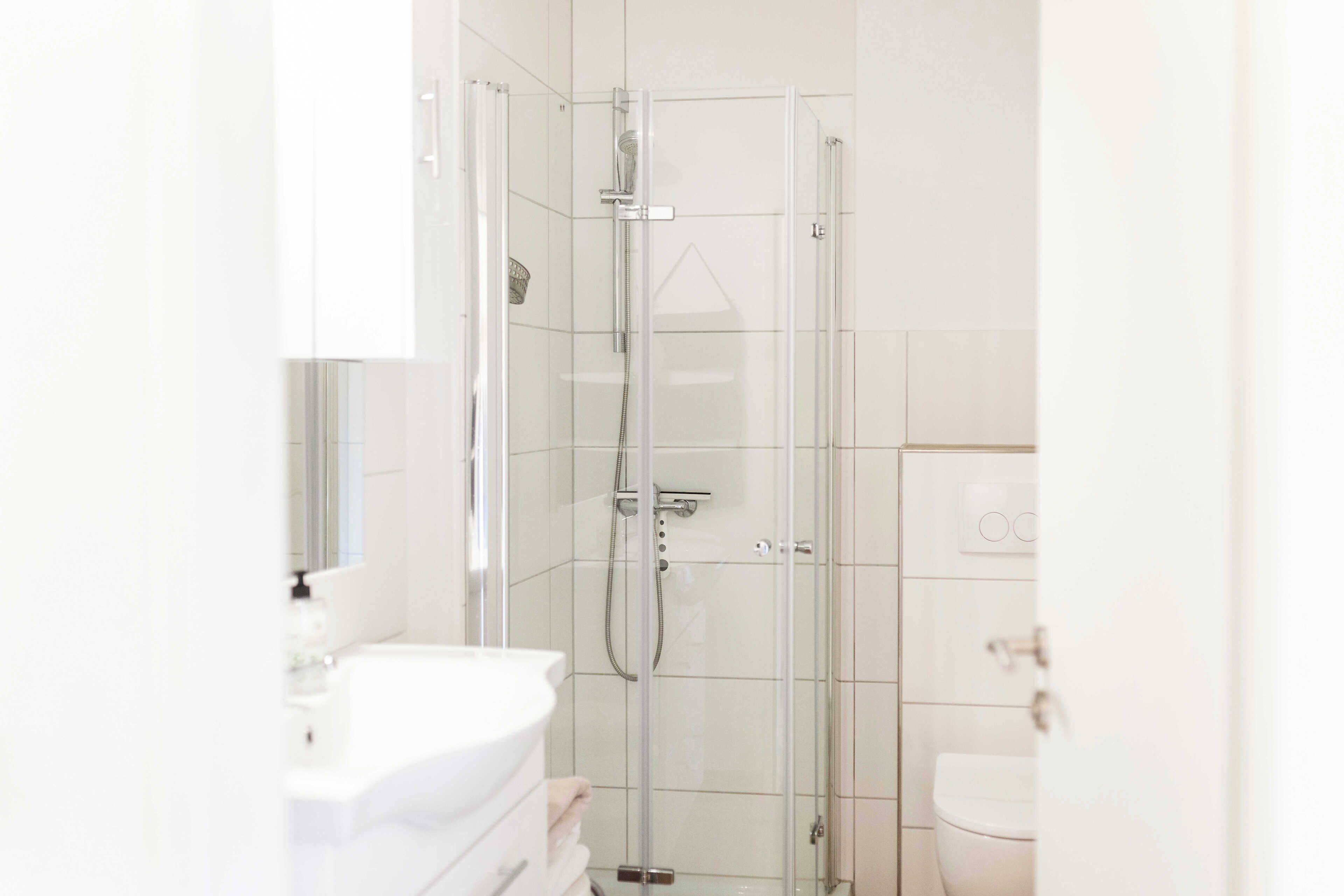 Un bagno moderno con doccia vetro, lavandino bianco e water.