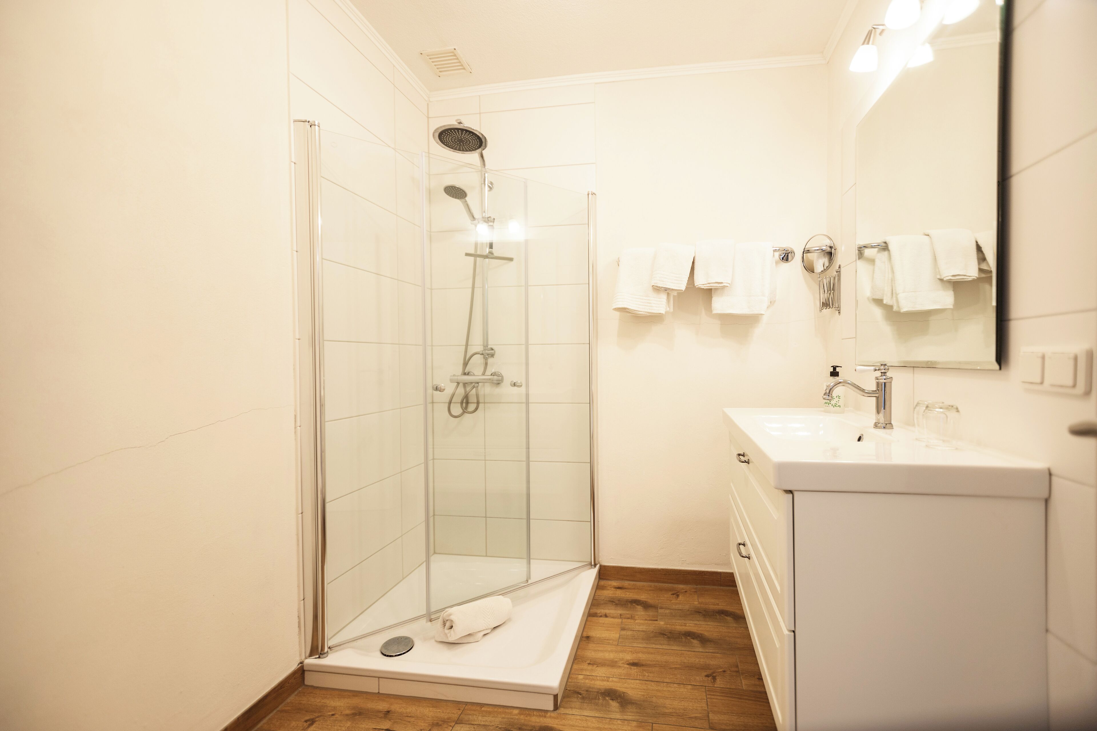 A modern bathroom with a glass-enclosed shower, a white vanity with a mirror, and neatly arranged towels.