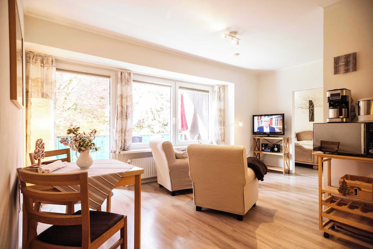 Una sala de estar con una mesa de comedor, sillas, un sofá, un televisor y una cafetera.