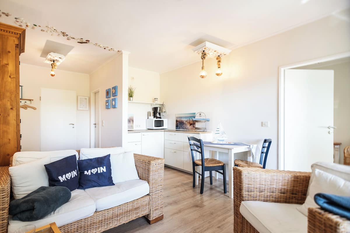 Una sala acogedora con un sofá, sillas de mimbre y una mesa de comedor.