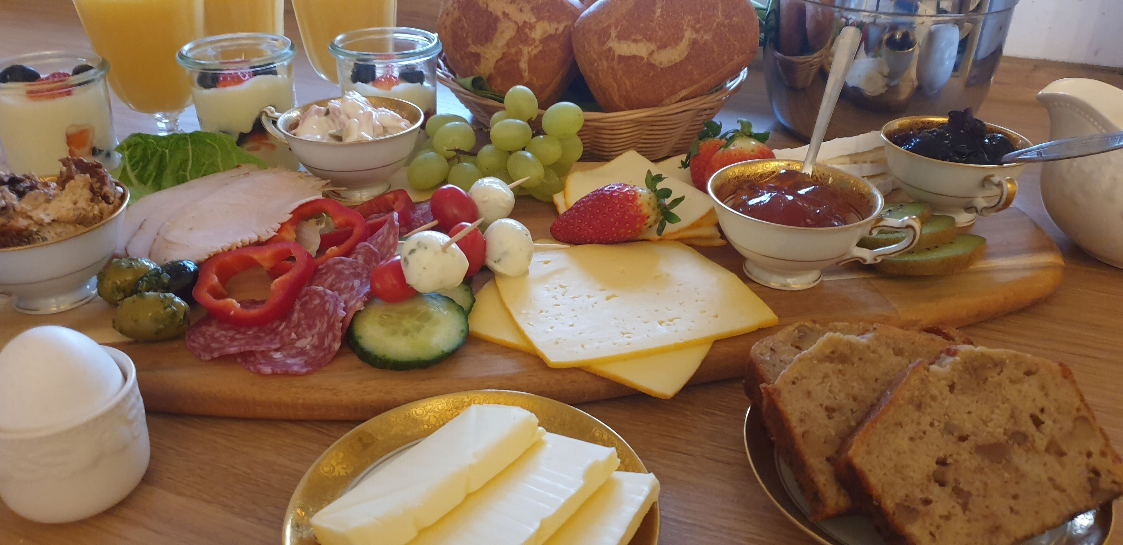 A breakfast spread with cheese, meats, fruits, and bread.