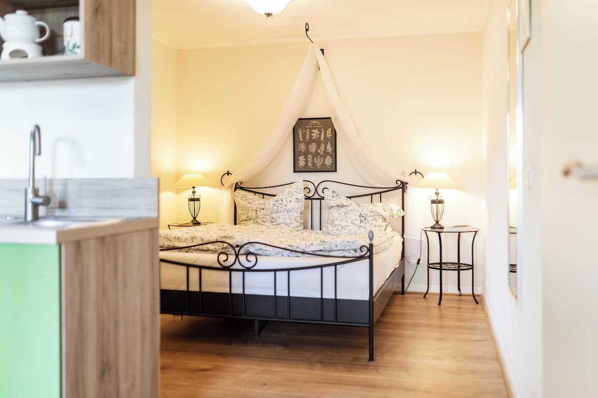 Un dormitorio con cama con dosel, lámparas de noche, una mesita y un cuadro enmarcado en la pared.