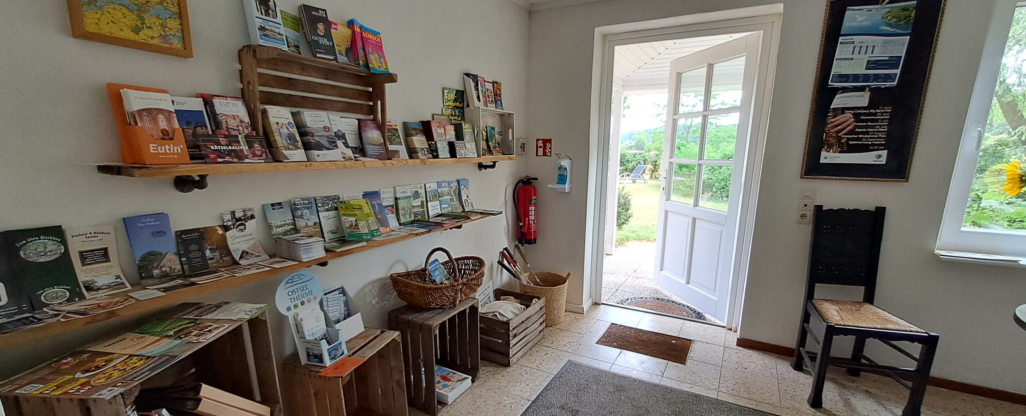 A bookstore with shelves of books, a fire extinguisher, a chair, and a door leading outside.