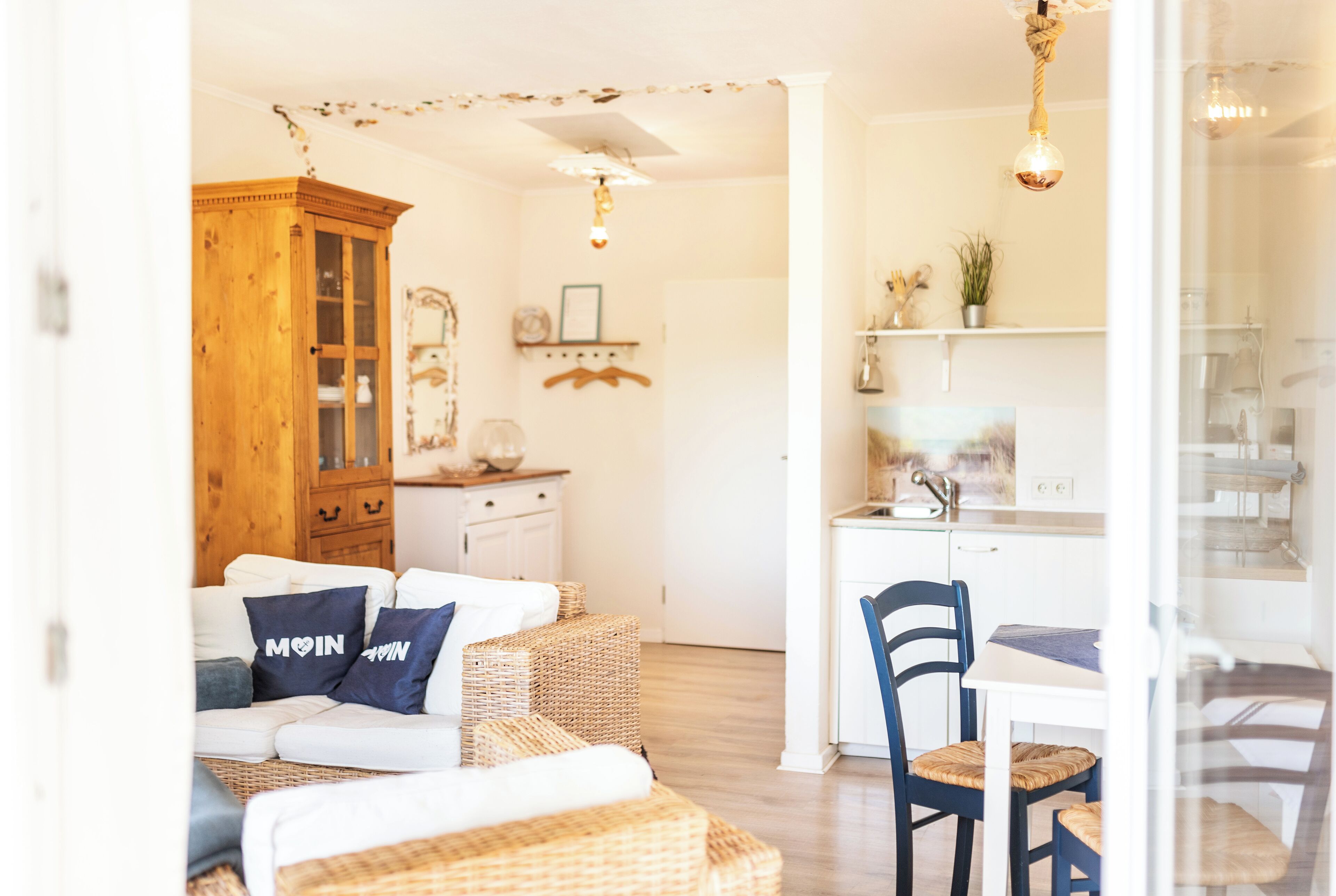 A cozy living room with a sofa, a wooden cabinet, and a dining area with a chair and table.