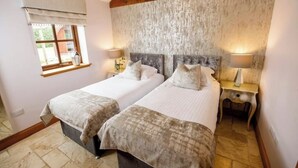 Une chambre avec un lit double, un plafond en bois rustique, deux tables de chevet avec des lampes et une fenêtre avec un rideau.