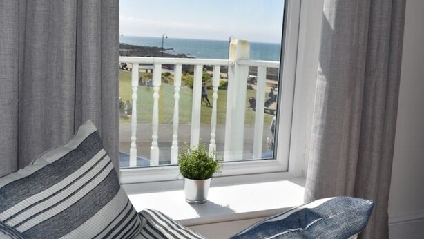 A balcony with a white railing, a potted plant, and a view of the sea. - Spacious Modern Apartment with Sea Views in Prime Beachside Location (Westward Ho!)
