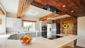 Een moderne keuken met een groot kookeiland, witte kasten en een rustiek plafond.