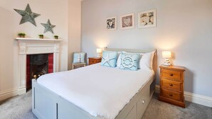 Ein Schlafzimmer mit einem weißen Bett, Wanddekoration in Form von Sternen, einem Kamin und gerahmten Bildern.