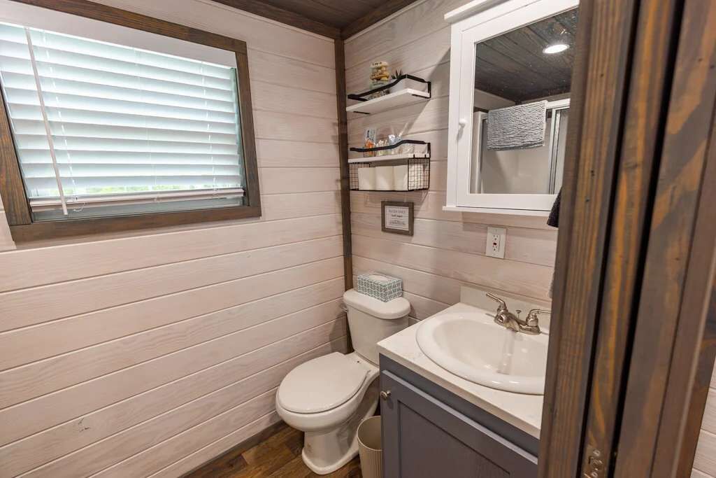 Ein kleines, kompaktes Badezimmer mit Toilette, Waschbecken und Fenster.