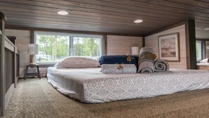 Een slaapkamer met een groot bed, een raam en een houten plafond.