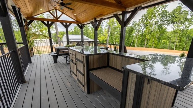 Een terras buiten met een houten vloer, een inpandige bar en uitzicht op de omliggende begroeiing.