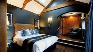 A modern bedroom with a large bed, a wooden ceiling, and a built-in wardrobe. - The Dairy - Rustic Retreats (Swansea)