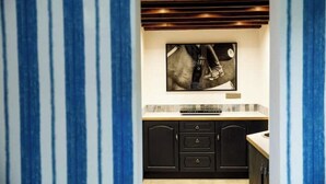 A kitchen with black cabinets, a tiled backsplash, and a framed artwork above the counter. - The Dairy - Rustic Retreats (Swansea)