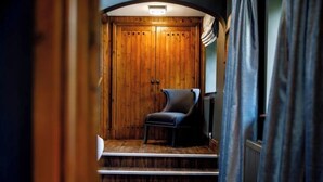 A room with a wooden wardrobe, a leather chair, and a radiator. - The Dairy - Rustic Retreats (Swansea)