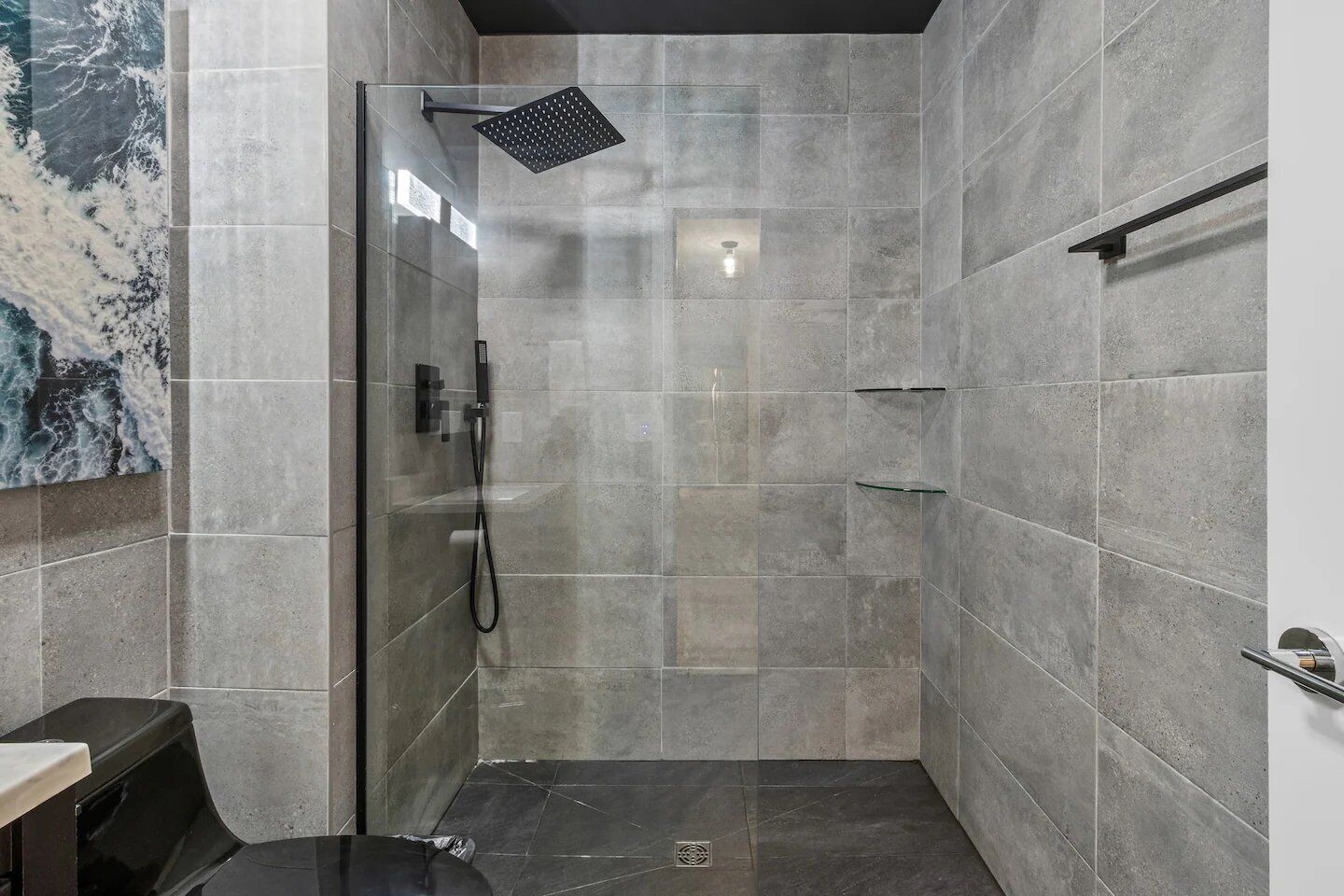 Un baño moderno con mampara de vidrio, un cabezal de ducha manual e iluminación empotrada en la pared.