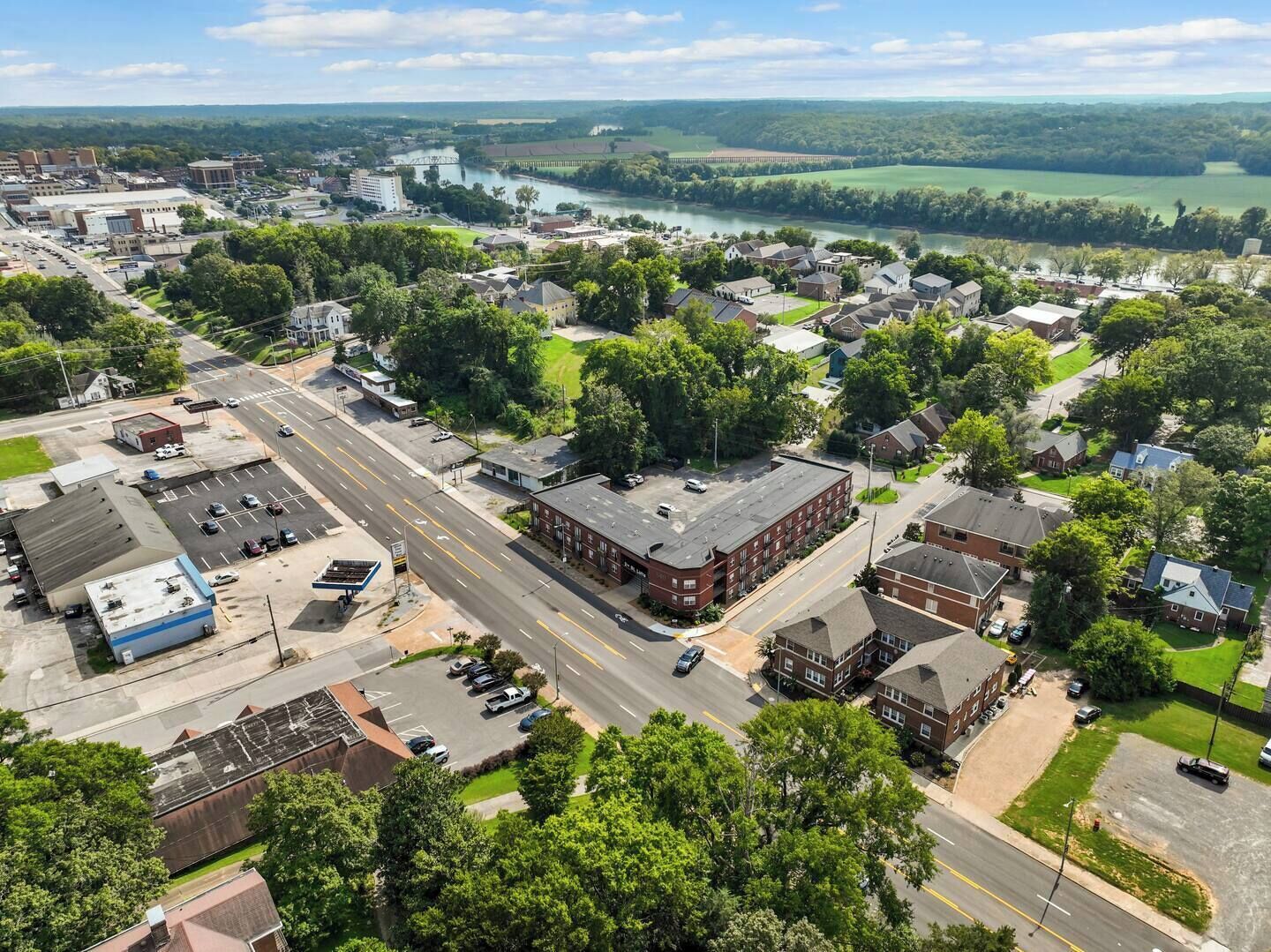 An aerial view of a town with a river, buildings, and green spaces.