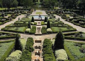 Un giardino formale con percorsi simmetrici, siepi curate e un elemento d'acqua centrale.