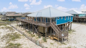 Una casa frente a la playa con una terraza de madera y un porche cubierto.