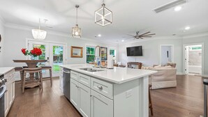 A modern kitchen with white cabinetry, a large island, and pendant lighting. - The Crab House: Built 2022. Huge property. Arcade. (Charleston)