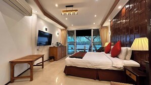 Habitación de hotel con cama, televisor, escritorio y vistas al exterior.