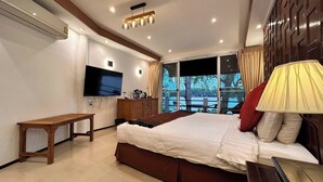 Habitación de hotel moderna con una cama grande, televisión, escritorio de madera y vistas al exterior.