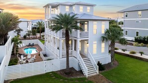 A two-story house with a balcony, a pool, and a well-maintained lawn.