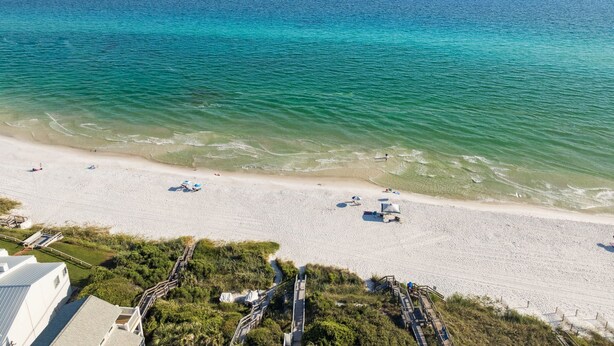 A beach with clear turquoise waters, a sandy shore, and a few umbrellas.
