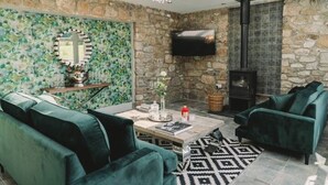 Una sala de estar acogedora con una pared de piedra, una chimenea y un televisor.