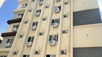 Un hotel de varios pisos con numerosas unidades de aire acondicionado en su fachada.