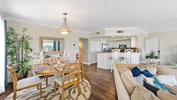 Un salon spacieux avec un grand canapé et un coin repas comprenant une table et des chaises en bois.