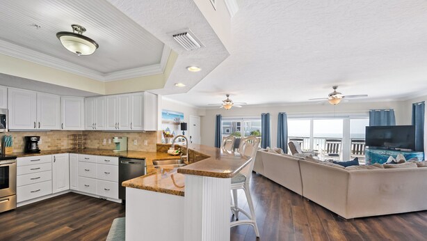 A modern kitchen with white cabinets, a granite countertop, and a built-in island. - Updated Spacious condo with Coastal Decor across from beach with peeks of Gulf (Bradenton Beach)