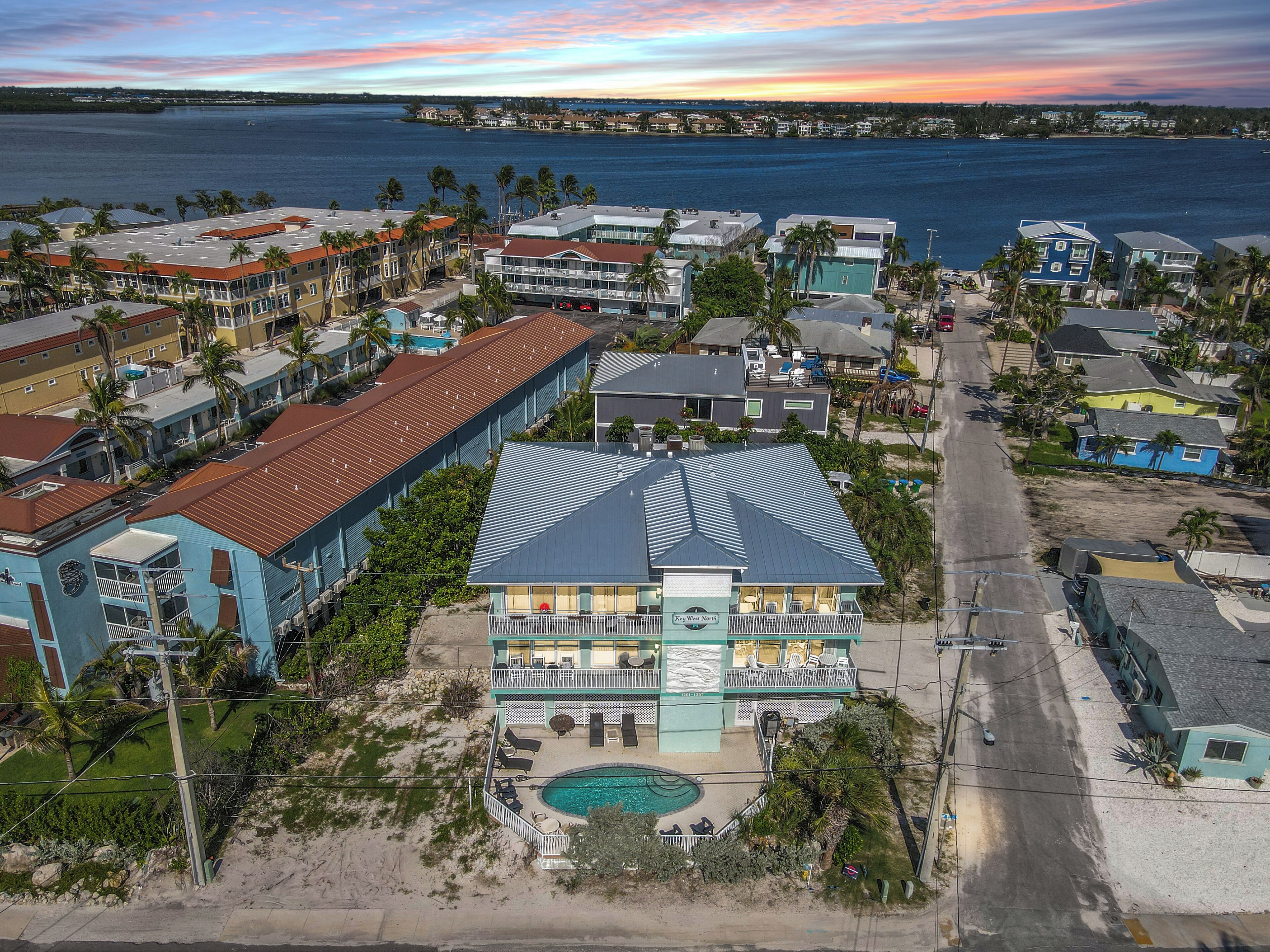 A beachfront hotel with a pool, multiple balconies, and a view of the ocean.