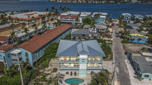 A beachfront hotel with a pool, multiple balconies, and a view of the ocean. - Updated Spacious condo with Coastal Decor across from beach with peeks of Gulf (Bradenton Beach)