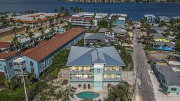 A beachfront hotel with a pool, multiple balconies, and a view of the ocean.