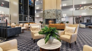 A spacious lobby with multiple seating areas, a central fireplace, and a high ceiling.