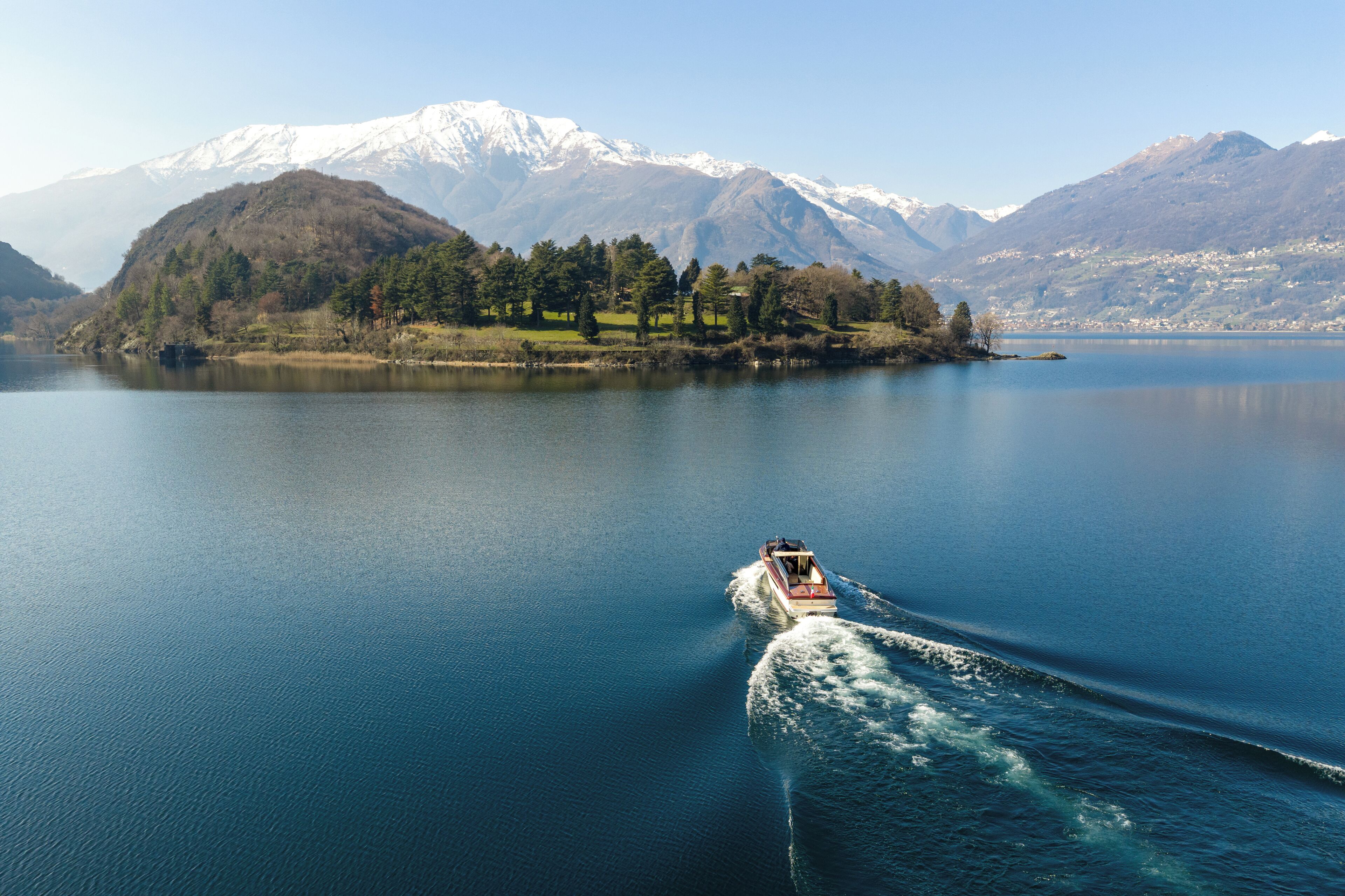 A boat on a calm lake with mountains in the background.