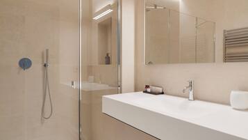 Une salle de bain moderne avec une douche à parois de verre, un lavabo blanc et un grand miroir.