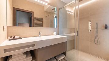 A modern bathroom with a glass-enclosed shower, a large mirror, and a vanity with a towel rack.
