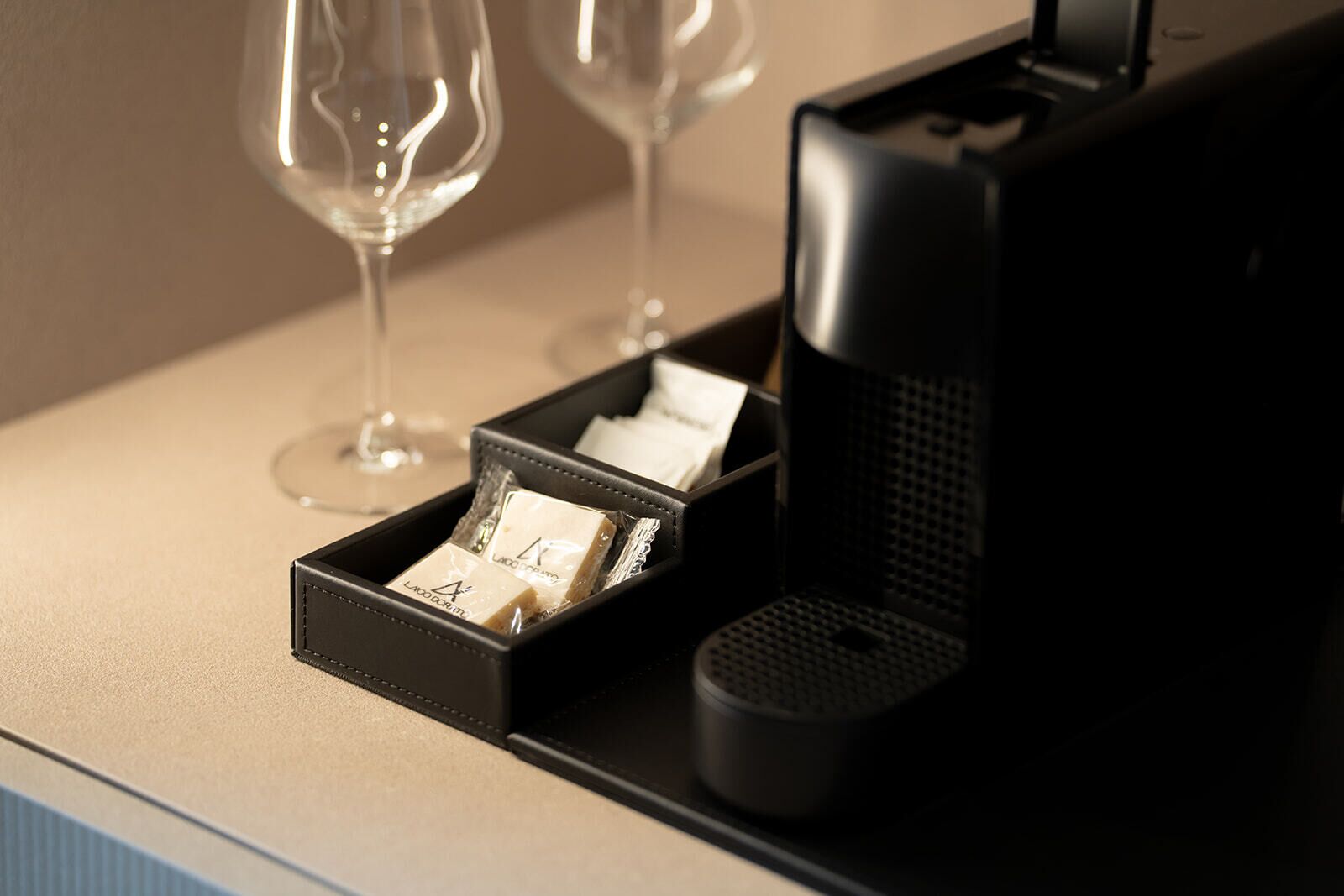 Une machine à café dotée d’un compartiment noir contenant des dosettes de café et d’un petit récipient.