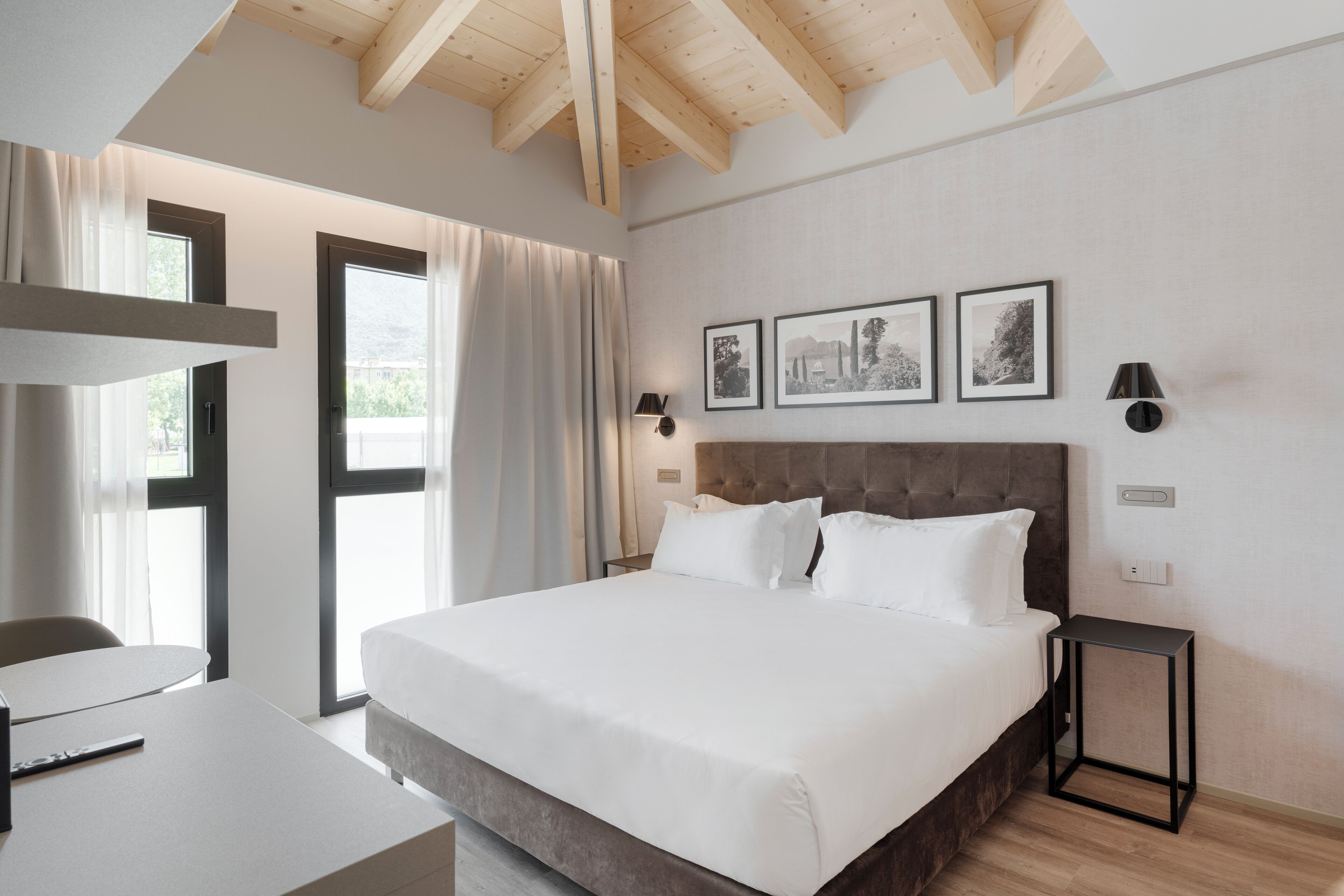 A modern hotel room with a large bed, a desk, and a window with curtains.