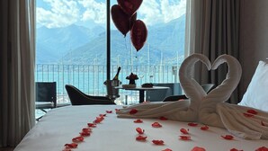Une chambre d’hôtel avec un lit, une vue sur la mer et un balcon équipé d’une table et de chaises.