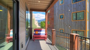 Un balcon avec vue sur les montagnes, un banc rouge et une porte vitrée.